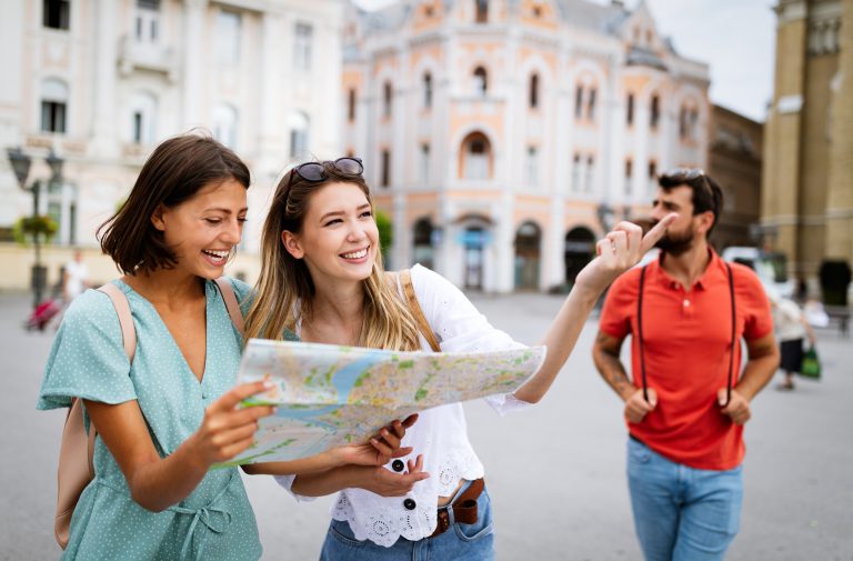 Happy traveling women tourists sightseeing with map in hand