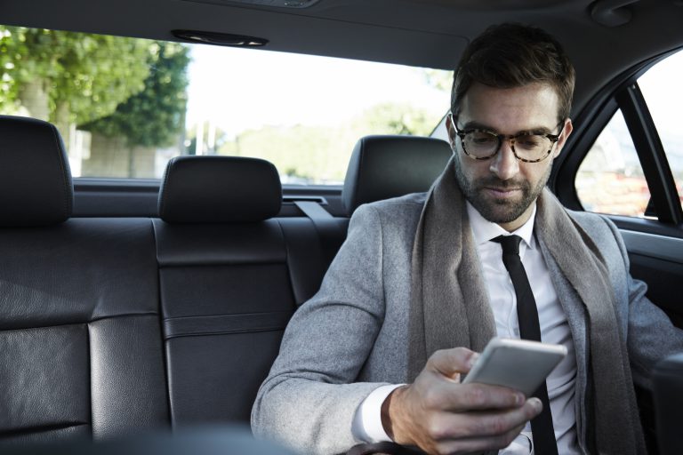 Businessman texting on smartphone in car